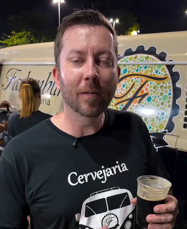 Anfitrião da Farbenblind com um copo de Stout em frente à Kombeer