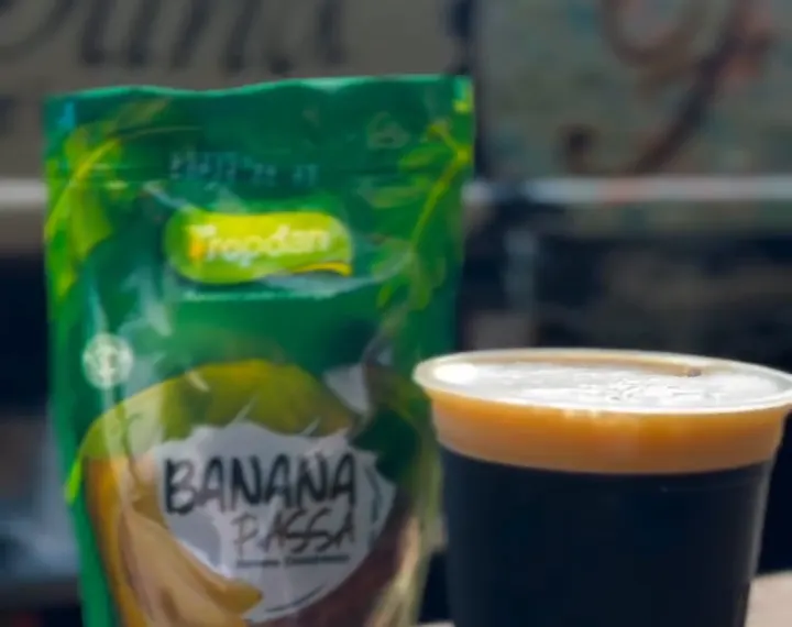 Copo de Stout ao lado de um pacote de banana passa Tropdan, em frente à Kombeer